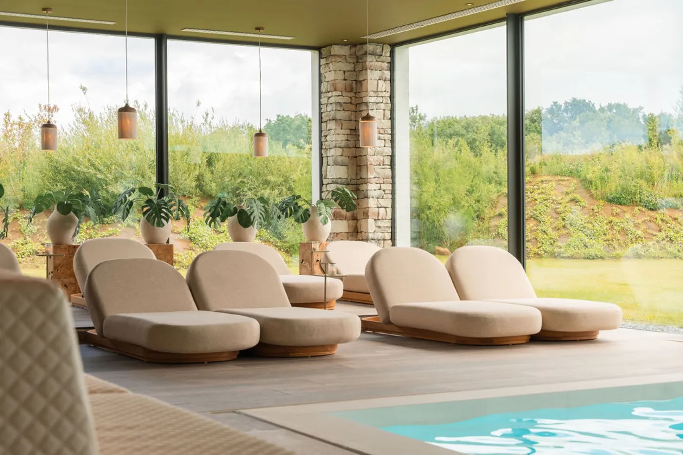 Spa loungers by the pool, facing tall windows and countryside views
